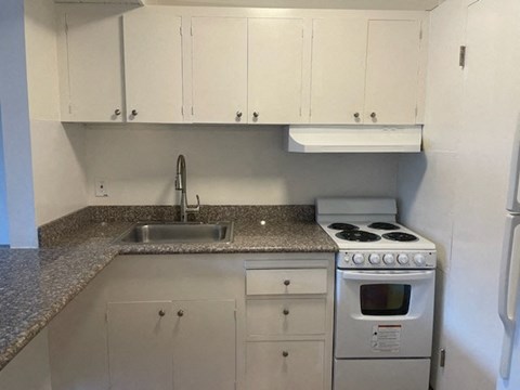 a kitchen with white cabinets and a stove and a sink