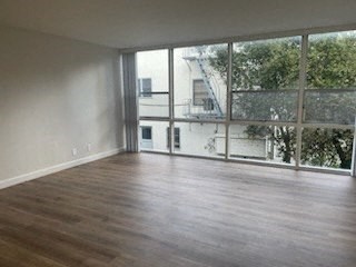 an empty living room with a large window and wooden floors