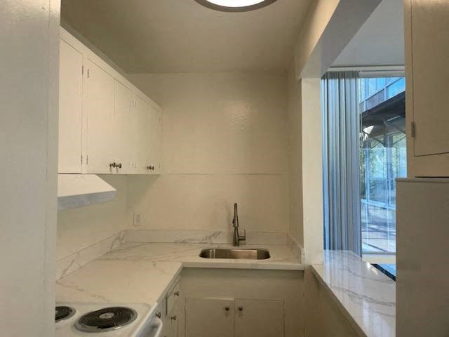 a white kitchen with a sink and a window