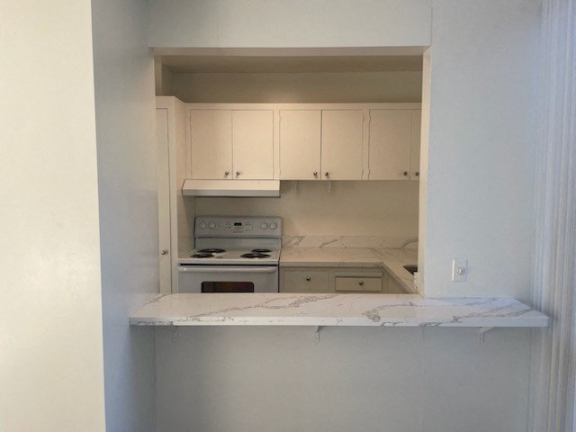an empty kitchen with white cabinets and a white counter top