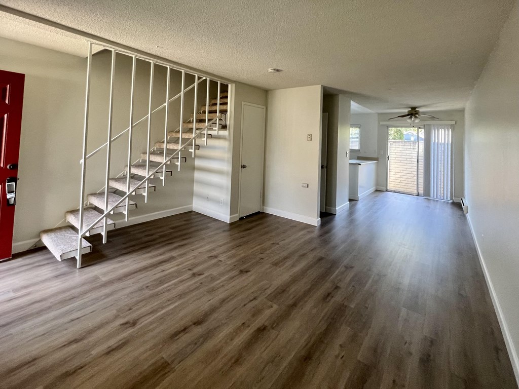 an empty living room with a staircase and hard wood floors