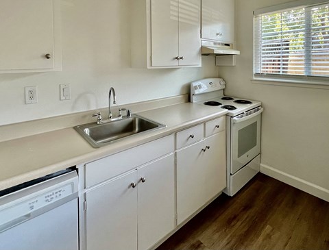 a kitchen with white cabinets and a sink and a stove