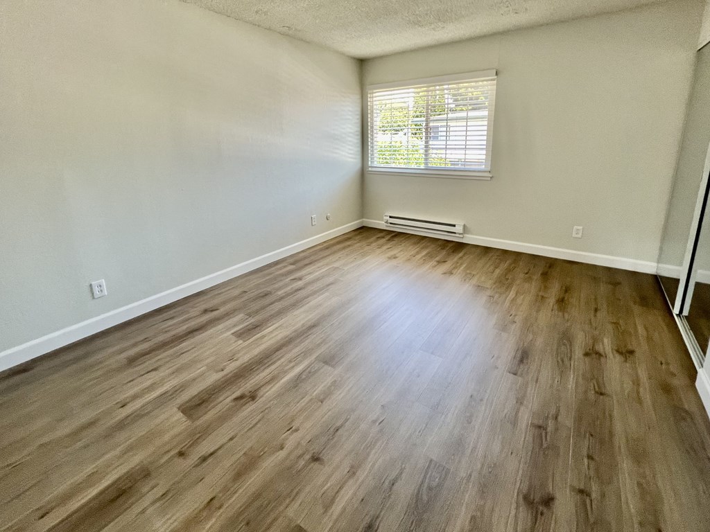 an empty living room with wood flooring and a window