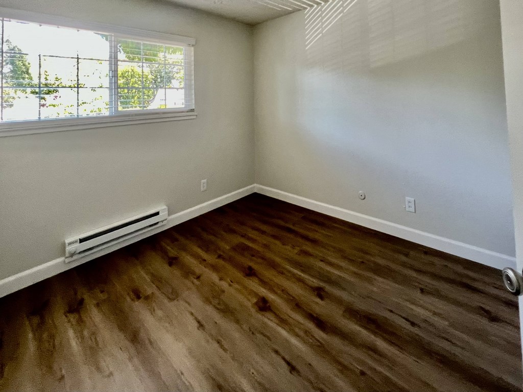 an empty room with wooden floors and a window