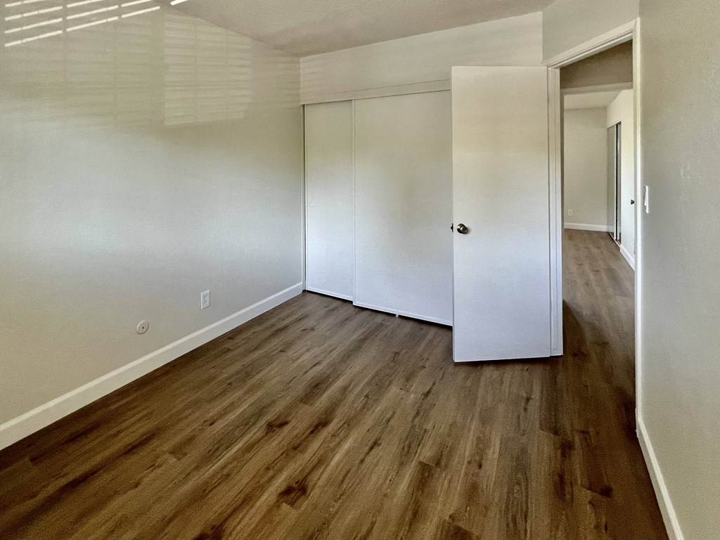 an empty room with white walls and a wooden floor