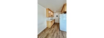an empty kitchen with wood flooring and a refrigerator