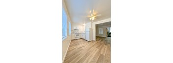 A kitchen with white appliances and wooden floors.