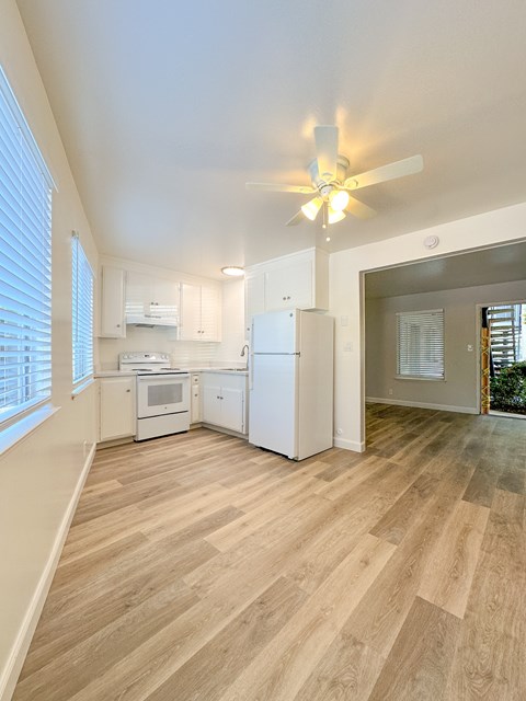 A kitchen with white appliances and wooden floors.