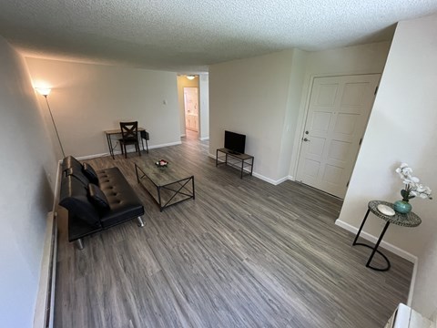 A living room with a black couch and a wooden floor.