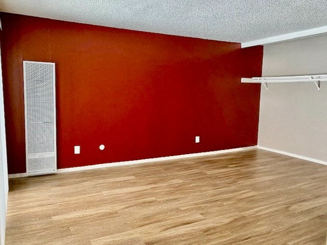 an empty room with a red wall and wooden floors
