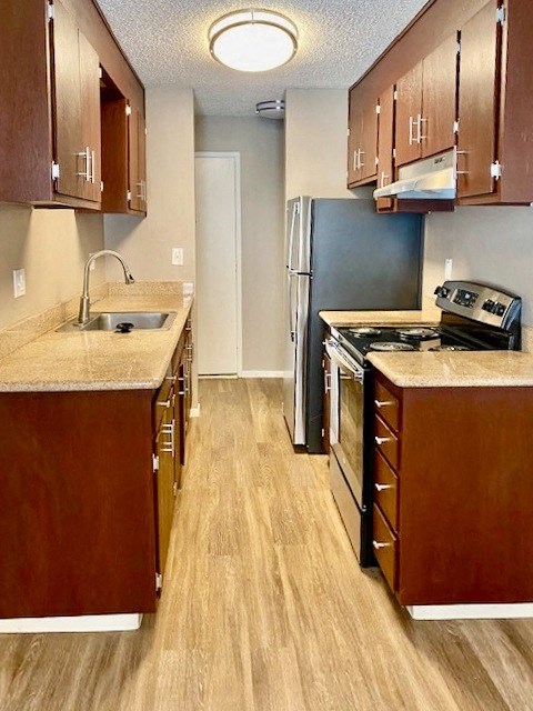 a kitchen with wood flooring and stainless steel appliances