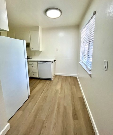 A kitchen with a white refrigerator and wooden floors.