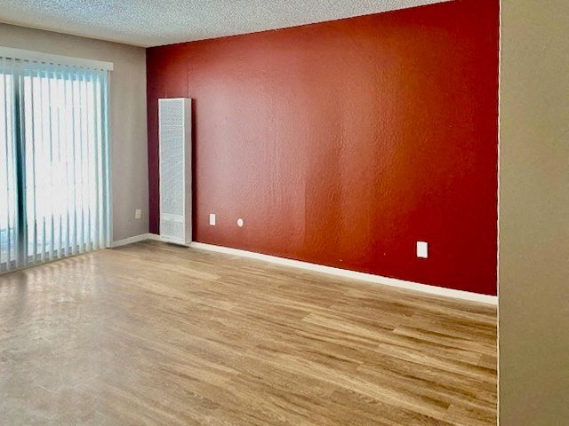 an empty living room with a red wall and wood floors