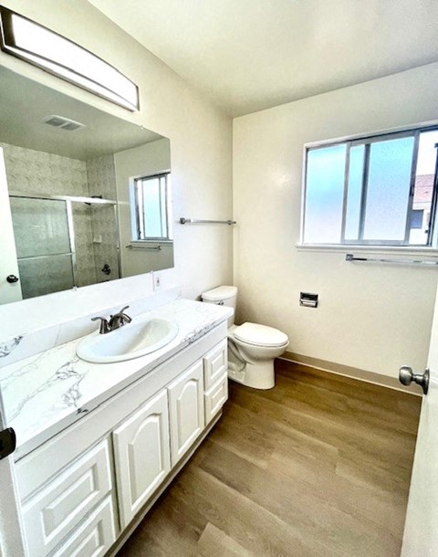 A bathroom with a toilet, sink, and mirror.