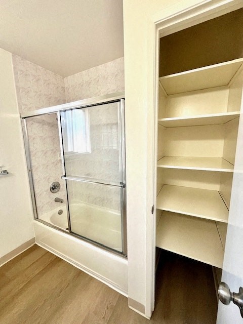 A white bathroom with a walk-in shower and a white cabinet with shelves.