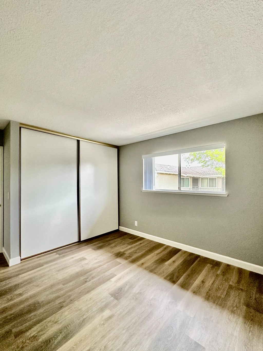 the spacious living room with wood flooring and a window