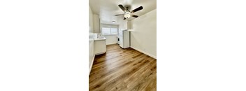 an empty kitchen with wood flooring and a ceiling fan