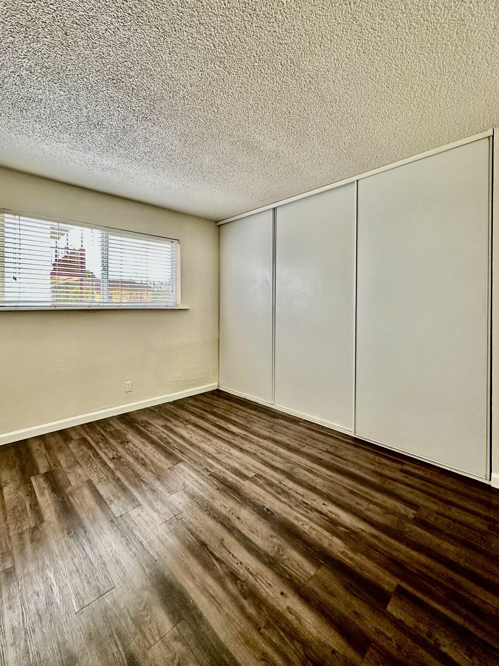 an empty living room with wood flooring and a window at The Chase Apartment Homes, Oakland, CA
