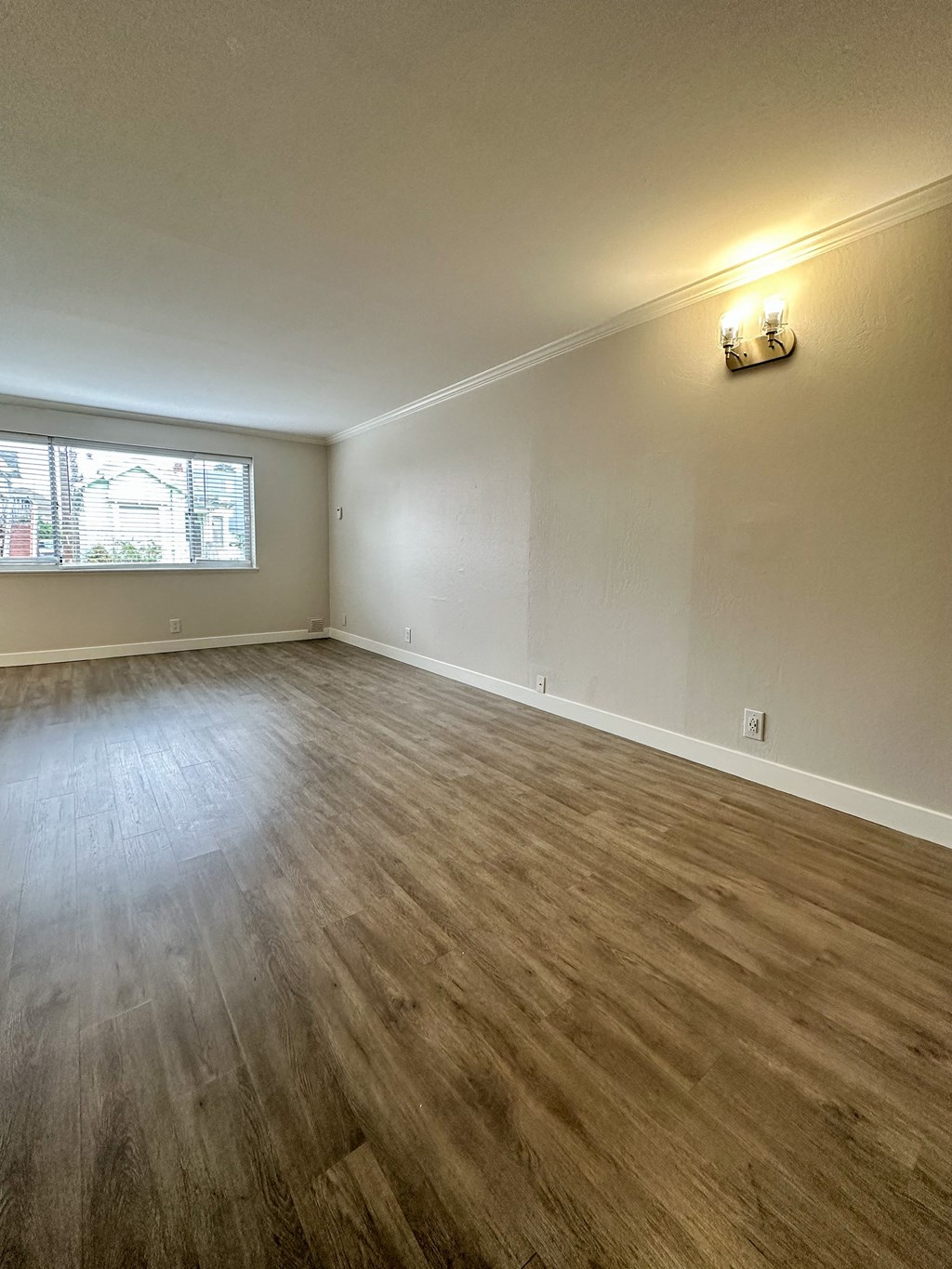 an empty living room with wood floors and a window at The Chase Apartment Homes, Oakland, CA