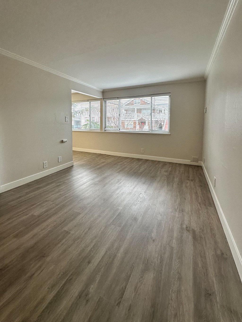an empty living room with wood floors and a window at The Chase Apartment Homes, Oakland California