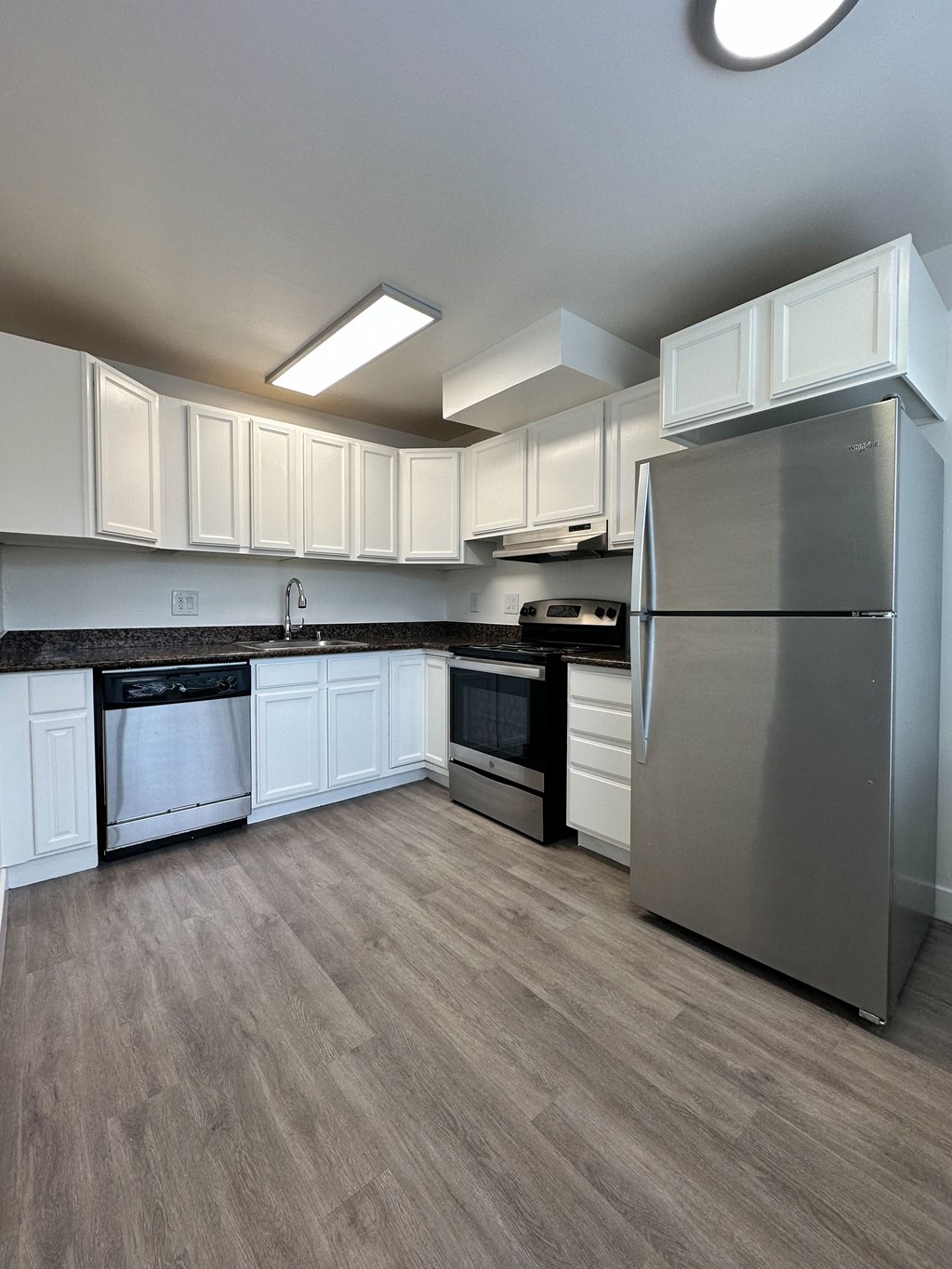 an empty kitchen with stainless steel appliances and white cabinets at The Chase Apartment Homes, Oakland, CA