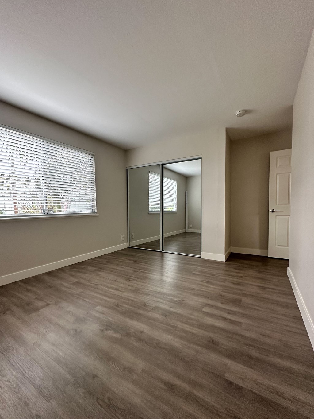 an empty living room with a large window and a door at The Chase Apartment Homes, Oakland, 94606