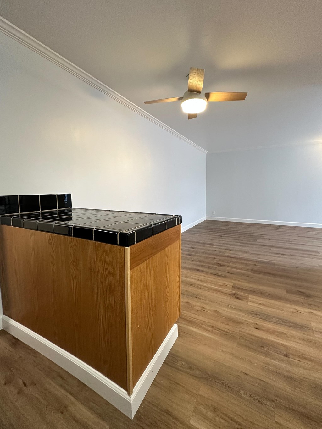 an empty living room with a kitchen island and a ceiling fan at The Chase Apartment Homes, Oakland