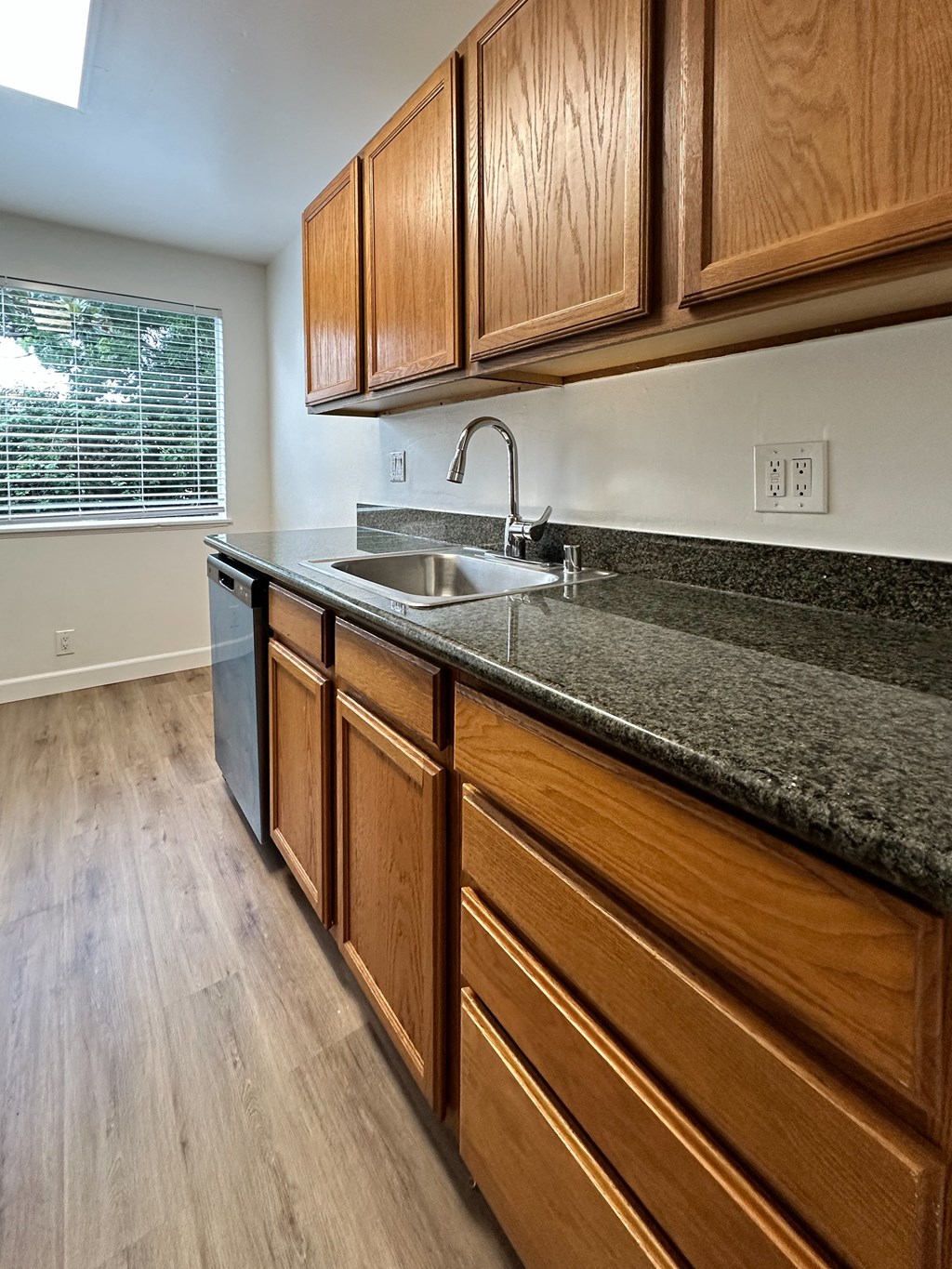 a kitchen with wood cabinets and granite counter top and a sink at The Chase Apartment Homes, California, 94606