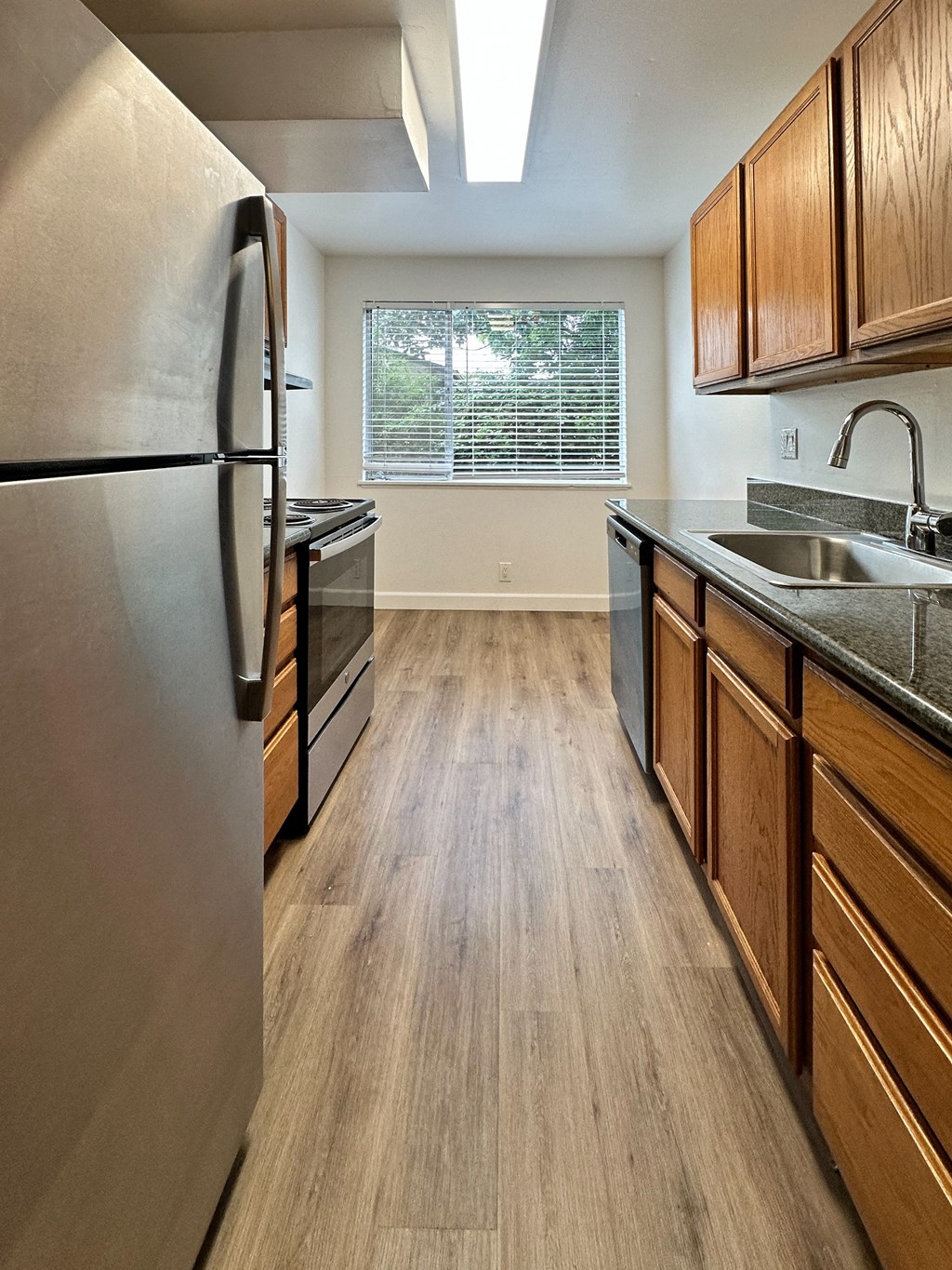 a kitchen with stainless steel appliances and wooden cabinets at The Chase Apartment Homes, California, 94606