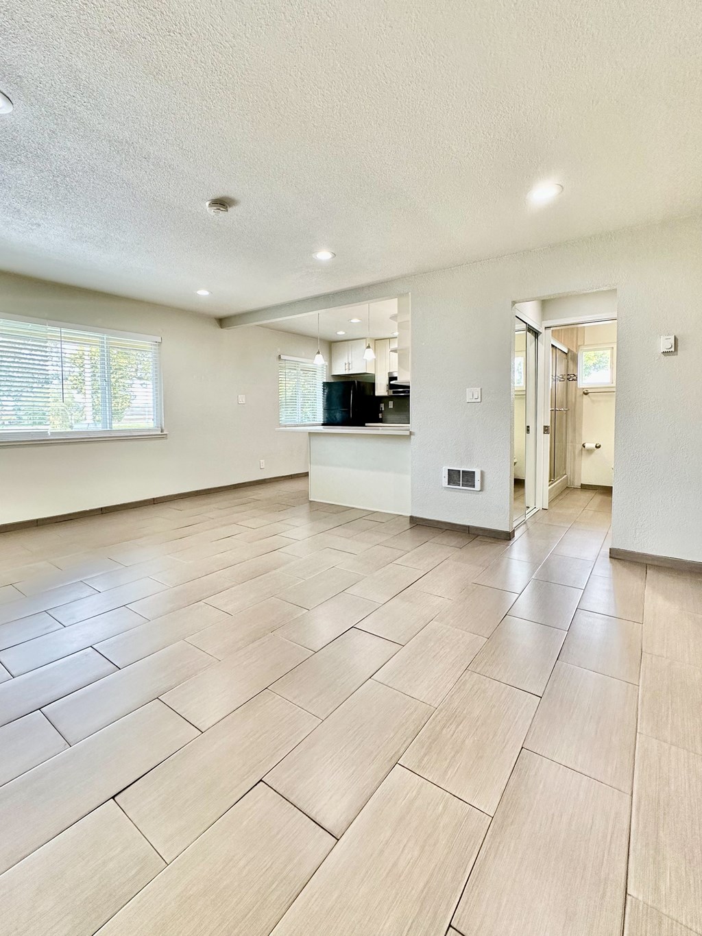 a spacious living room with a kitchen and a large tiled floor