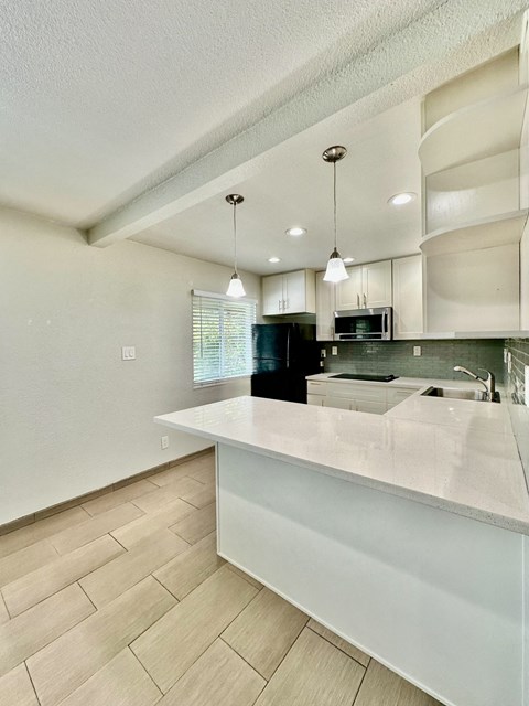 a white kitchen with a large island and a black refrigerator