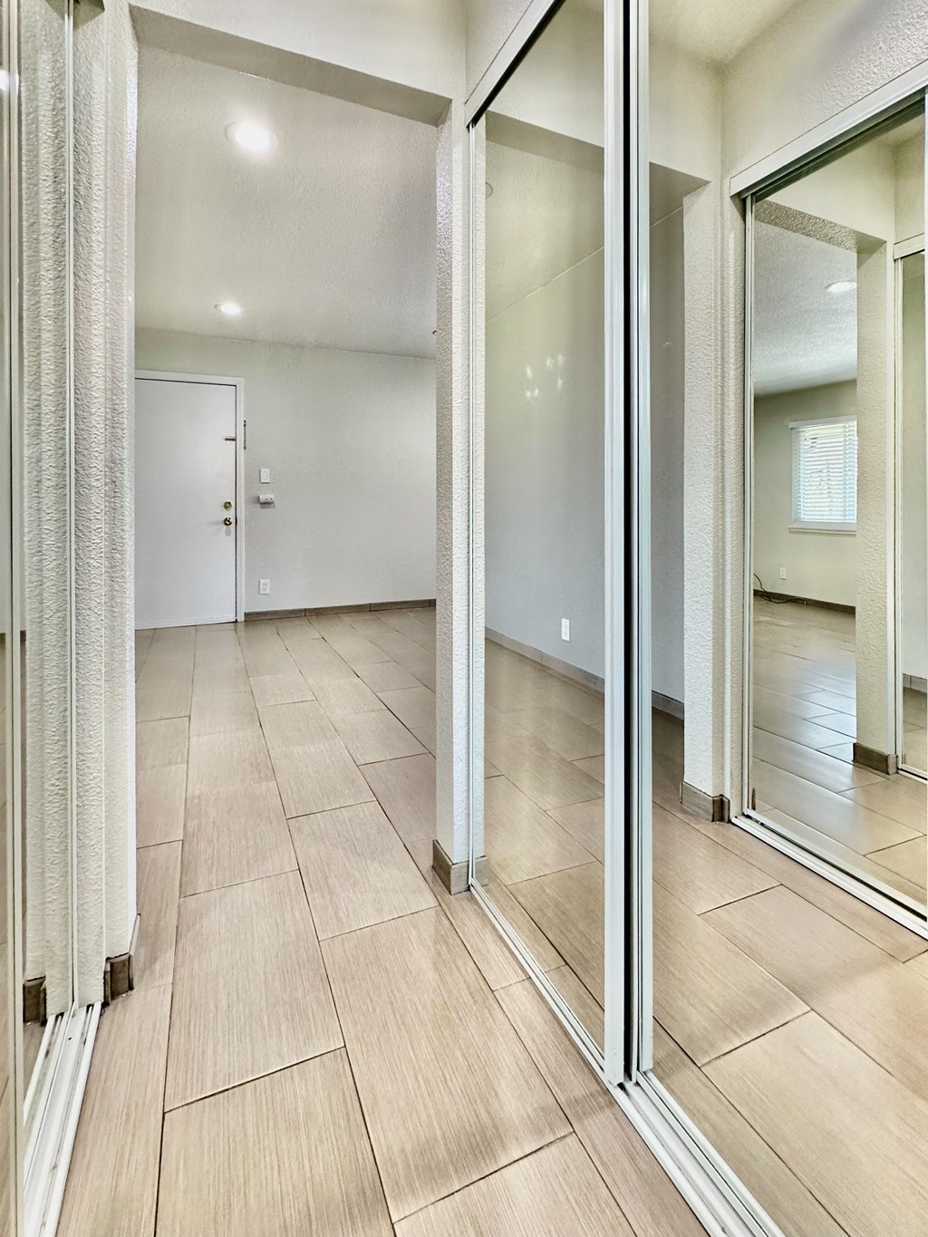 the living room has large mirrors and a large tiled floor