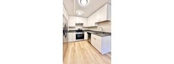 A modern kitchen with white cabinets and a wooden floor.