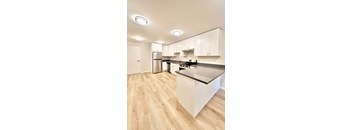 A kitchen with white cabinets and a wooden floor.