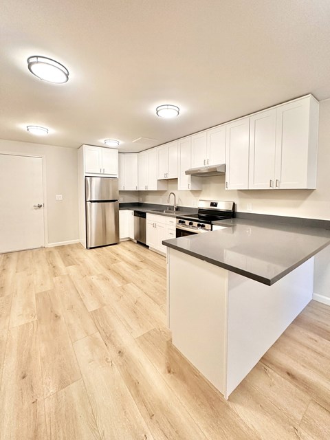 A kitchen with white cabinets and a wooden floor.