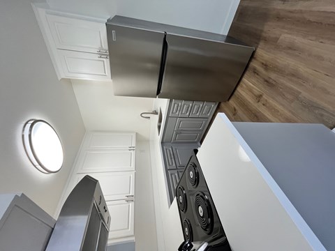 A modern kitchen with a stainless steel refrigerator and a wooden floor.