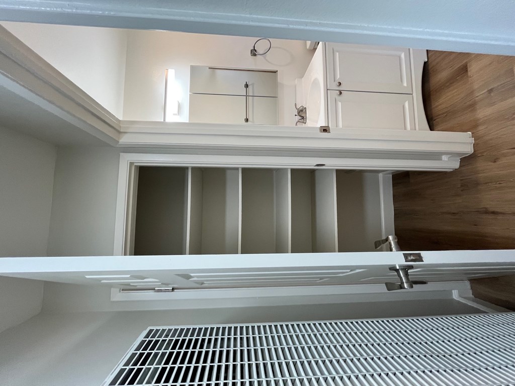 A white refrigerator with its door open and a drain grate at the bottom.