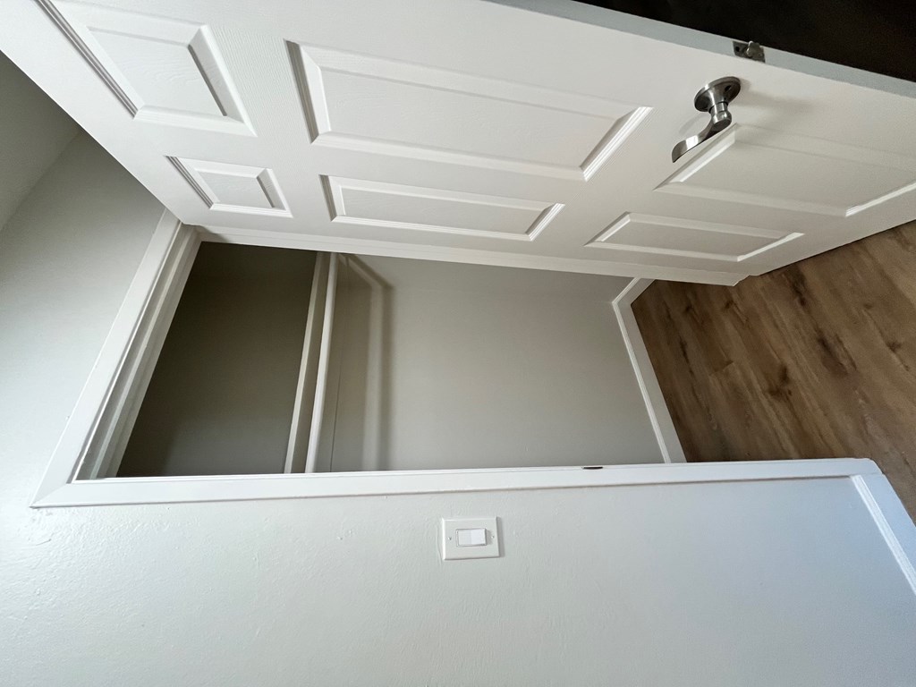 A white ceiling with a light switch and a white door.