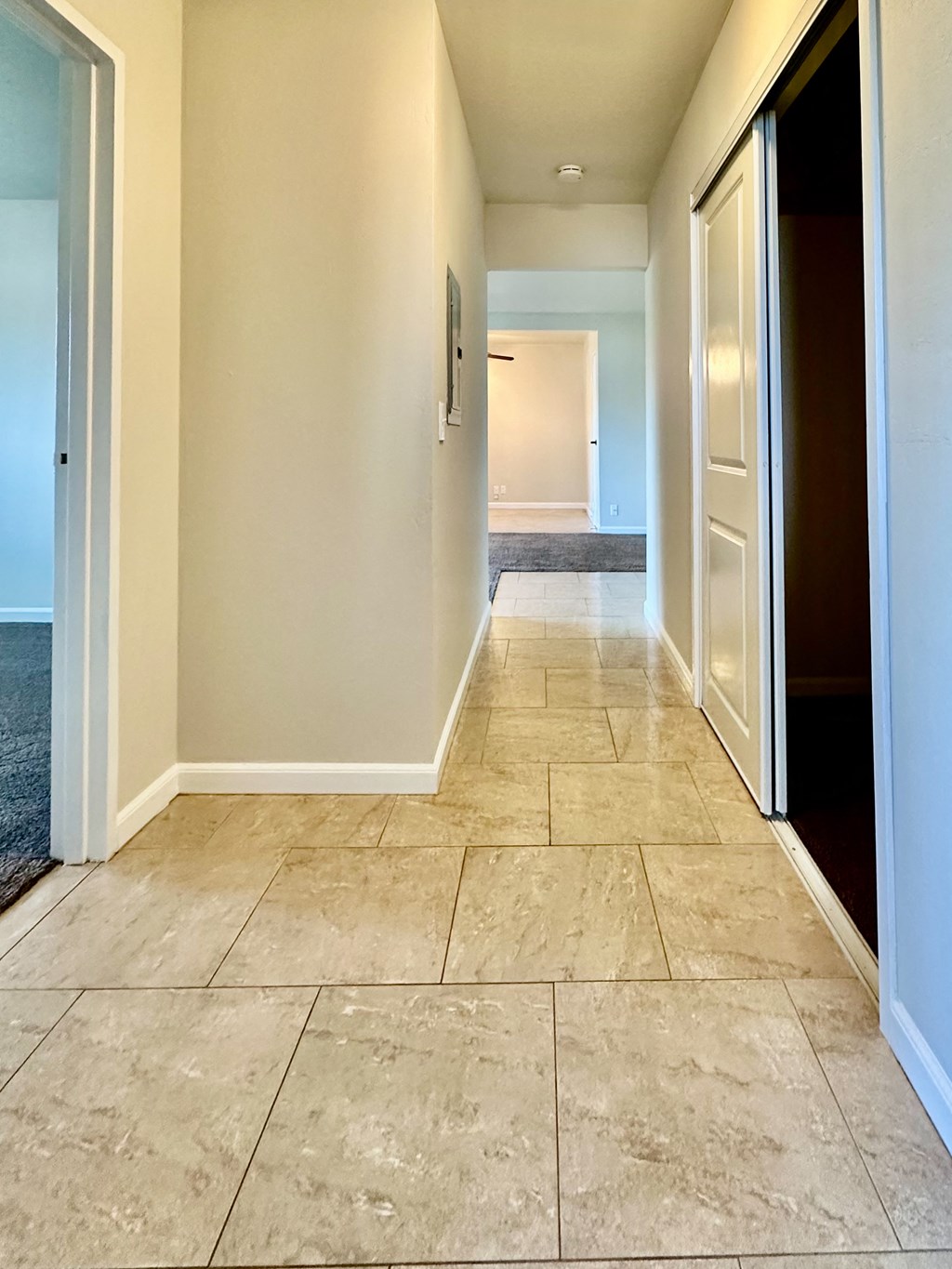 an empty hallway with a tiled floor and open doors