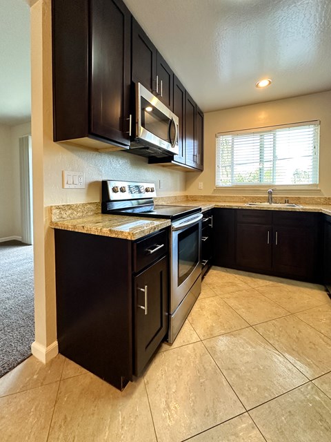 A kitchen with black cabinets and a granite countertop.