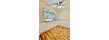 an empty bedroom with a large window and a ceiling fan