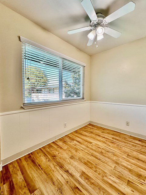 an empty bedroom with a large window and a ceiling fan