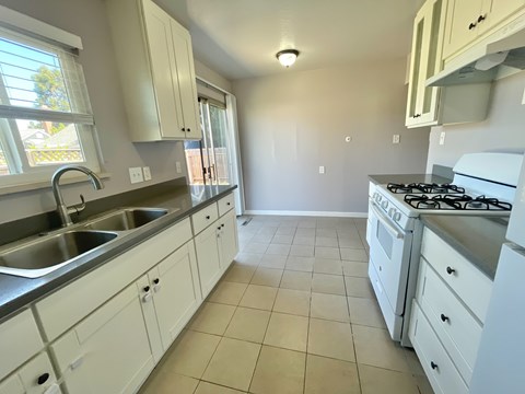A kitchen with white cabinets and a stove top oven.