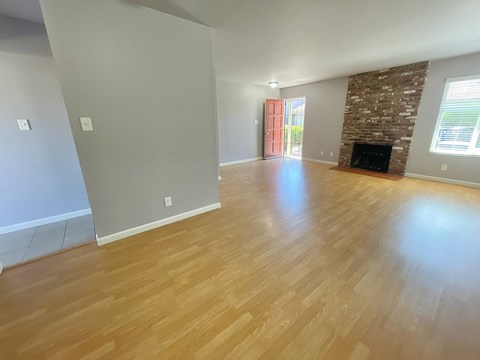 A room with wooden flooring and a stone fireplace.