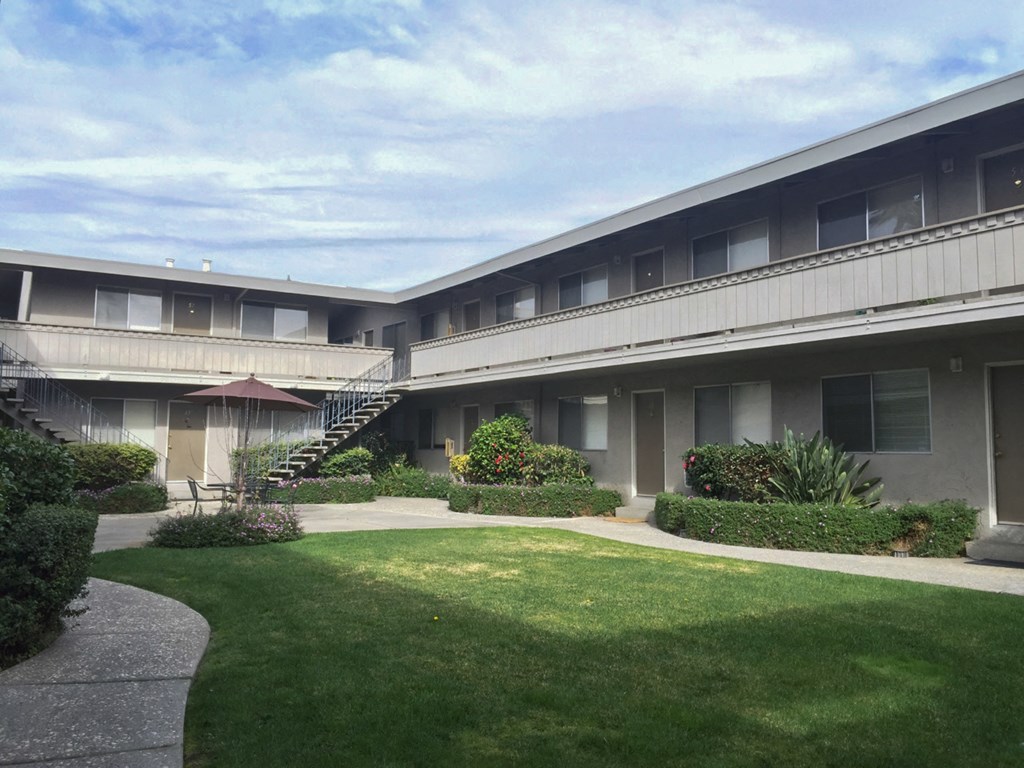 the courtyard of an apartment building with a lawn and a staircase