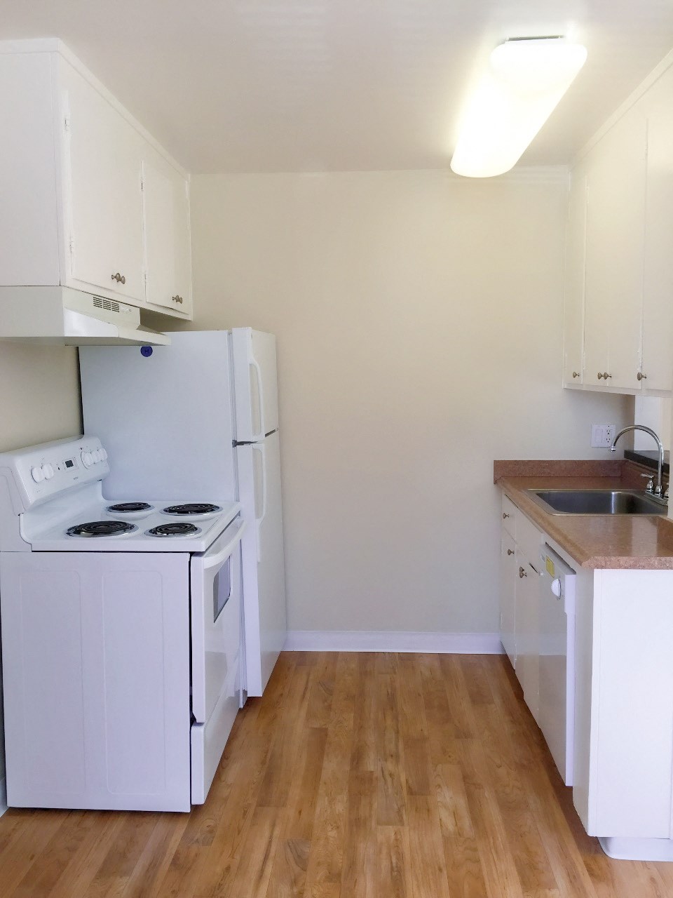 an empty kitchen with a stove refrigerator and sink