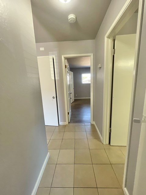 A hallway with white walls and tile flooring.