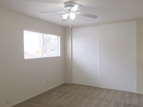 an empty living room with a ceiling fan and a window