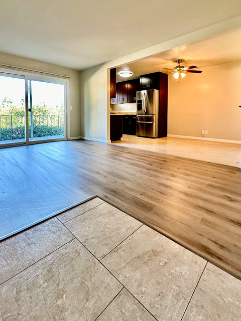 A spacious room with wooden floors and a kitchen area in the background.