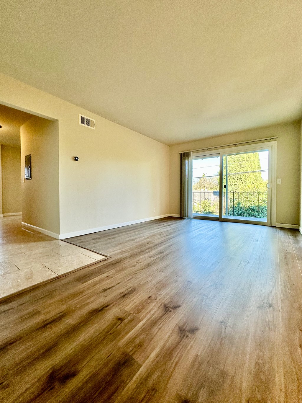 an empty living room with wood floors and a sliding glass door